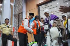 Salah satu Jemaah Calon Haji kloter 97 hendak menuju bis yang mengangkutnya ke bandara Juanda. (Foto : Eleanor/tagarjatim.id)